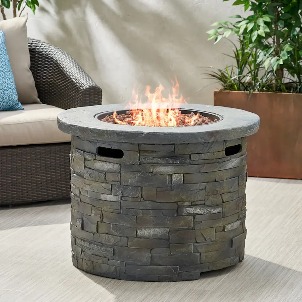 Stone fire pit on patio with blazing fire.