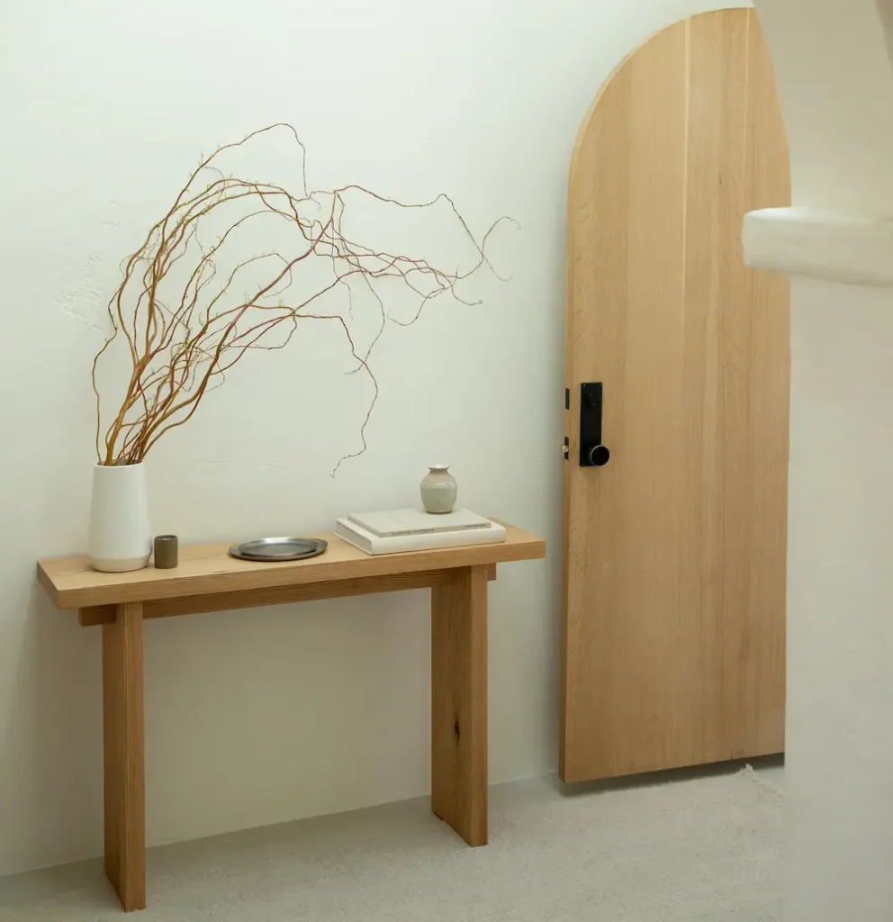 Minimalist wooden console table with decor by door.