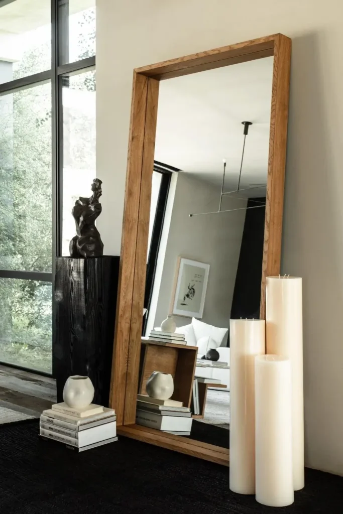 Large floor mirror with candles and sculpture in room.