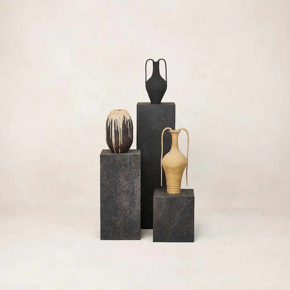 Decorative ceramic vases on pedestals with neutral background.