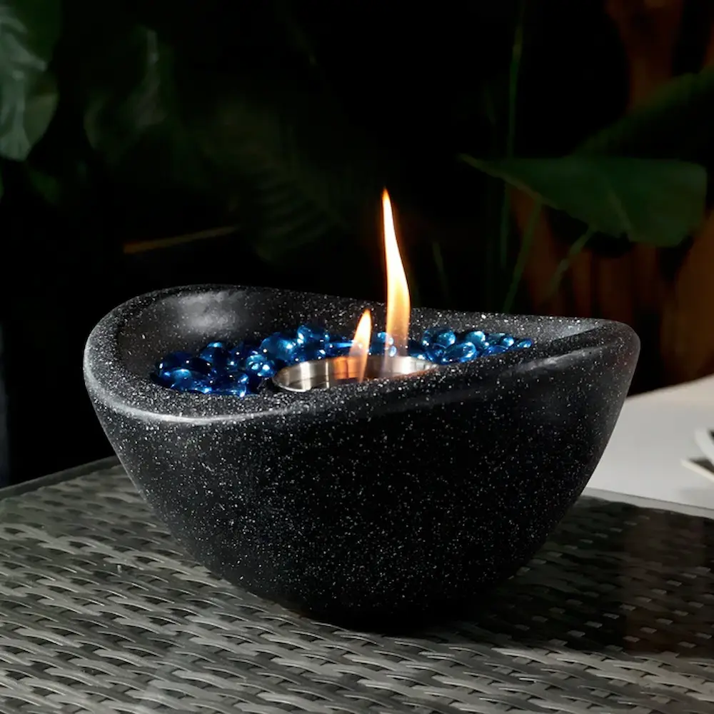 Lit candle in black bowl with blue gems.