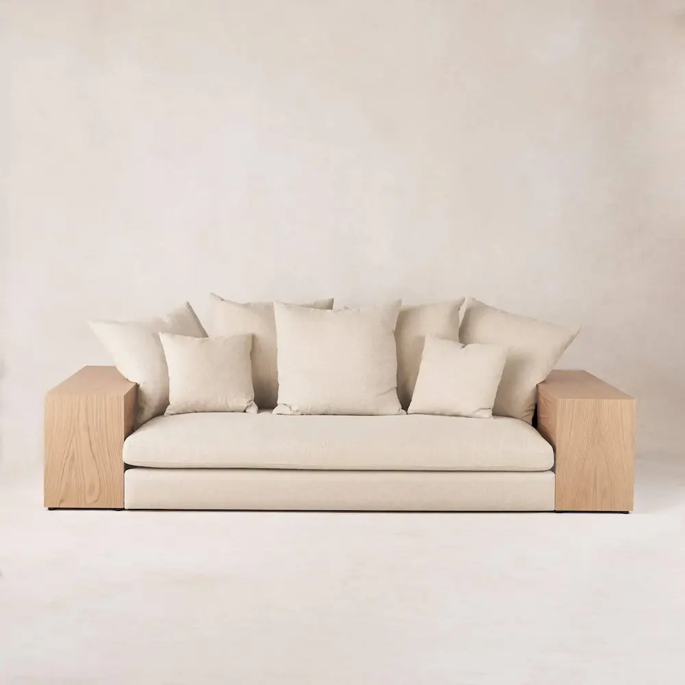 Modern beige sofa with cushions on neutral background.